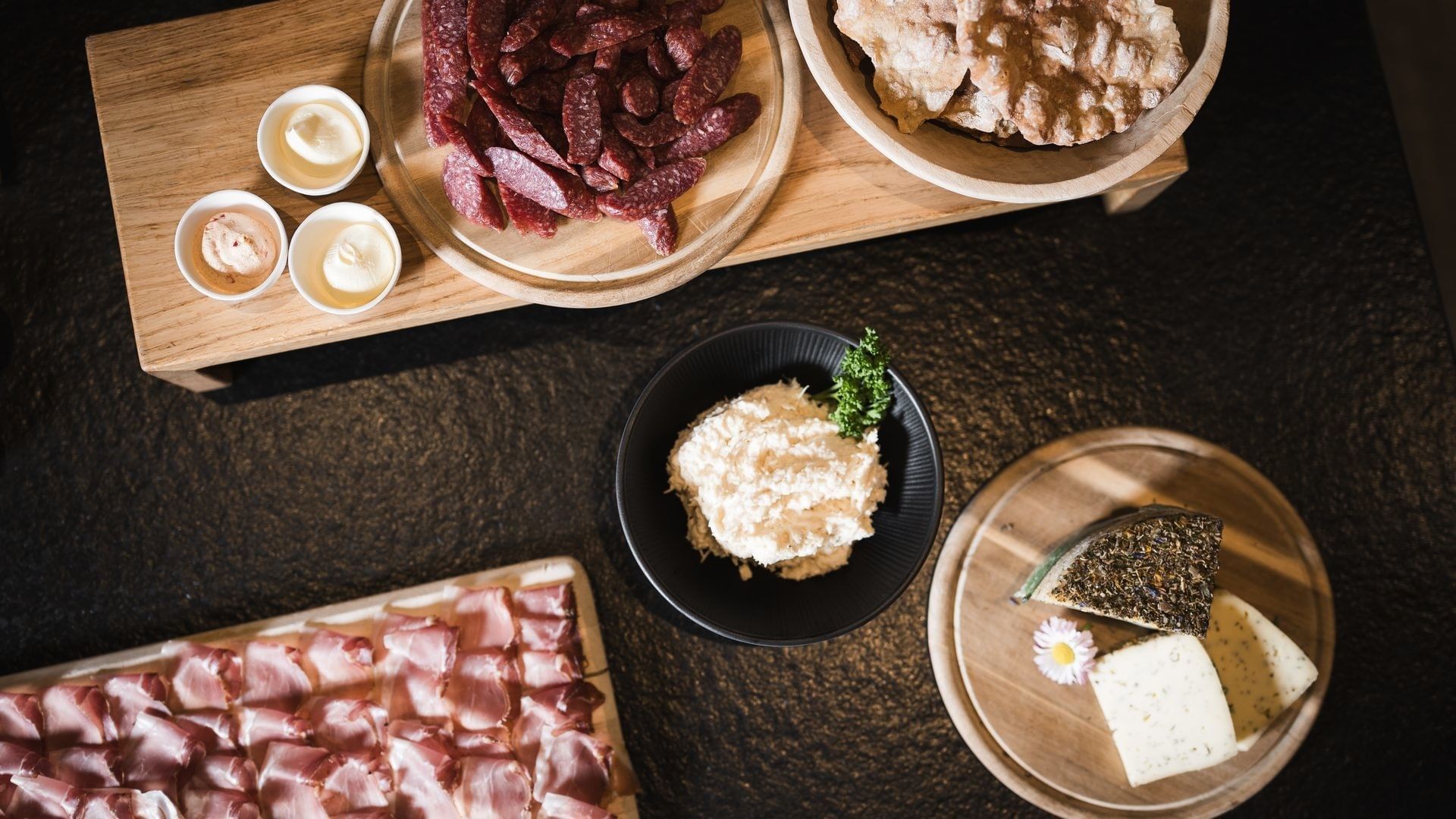 Verschiedene Wurstsorten und Käse auf Holzbrettern und in Schüsseln am Falkensteinerhof