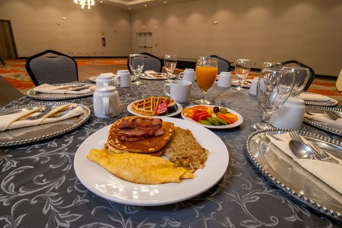 Breakfast plates with eggs and waffles by coffee mugs on a table surrounding formal event chairs at Hotel Mirra
