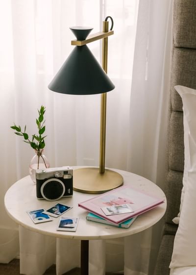 Best hotels in South Beach Miami, nightstand with a modern lamp and a Polaroid camera by a sheer curtain at Kenmore Village