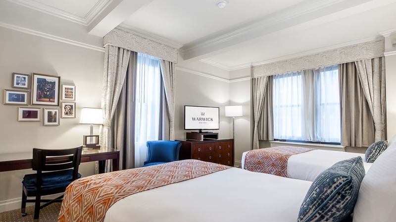 Comfy twin bed with side tables and Tv in Premier City View Suite at Warwick New York