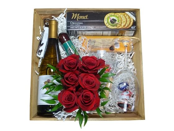 A box containing a bottle of wine, roses, glasses and crackers