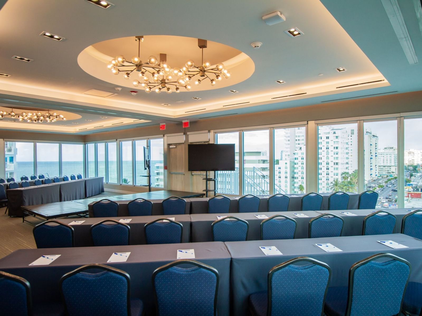 meeting room with rows of tables and chaird with television set up