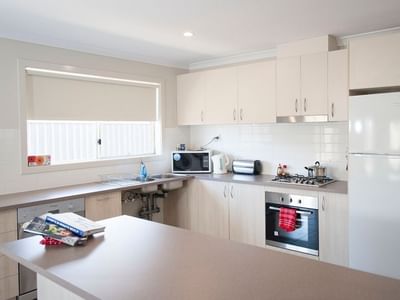 Modern kitchen with white appliances and cabinets at La Trobe University Regional Housing Shepparton.