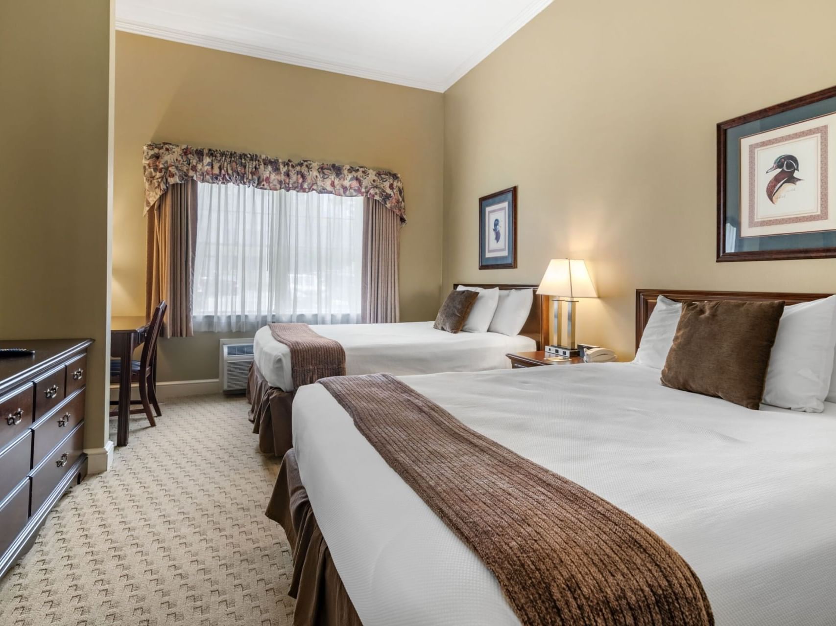 Two beds, workspace & nightstand in Superior Suites at The Bethel Inn Resort & Suites