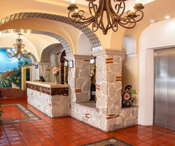 Lobby area featuring stone pillars and arched tiled hallways leading to the front desk and elevator at Casa Dona Susana