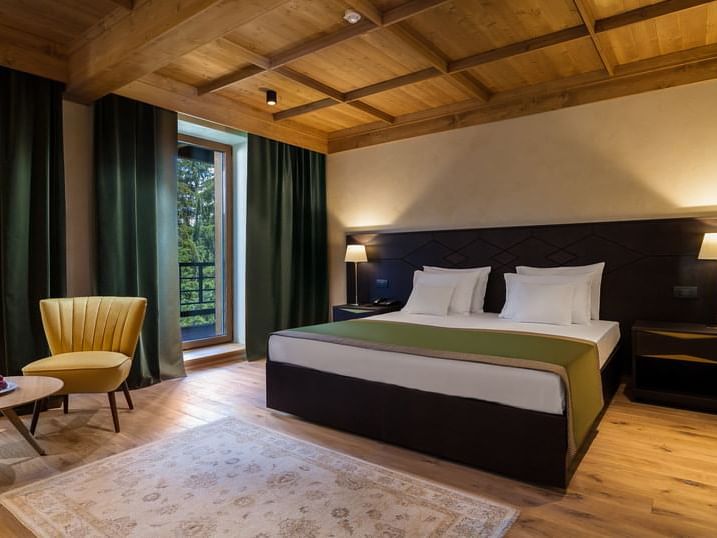 Lounge area by the bed in King Deluxe Room with wooden floors at Ana Hotels Bradul Poiana Brașov