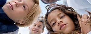 Diverse family smiling in a circle under a blue sky.