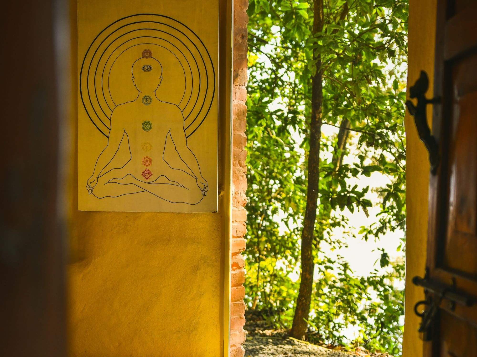 Indoor chakra meditation poster on yellow wall, framed by lush greenery at Dwarika's Himalayan Wellbeing