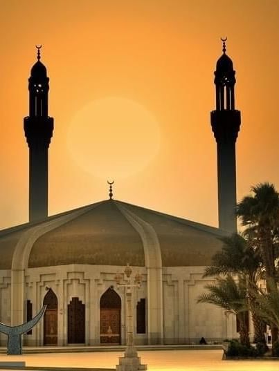 Hassan Enany Mosque with two tall minarets stands at sunset, framed by a warm orange sky near Warwick Hotel Jeddah