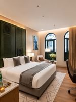 King bed with arched window views beside desk with chair and welcome treats in Accessible Room at Naviti by Warwick Jeddah