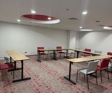 Sala Fagua con mesas de madera en forma de U y sillas bajo luces empotradas en Unika Hotels, centro de eventos en Colombia