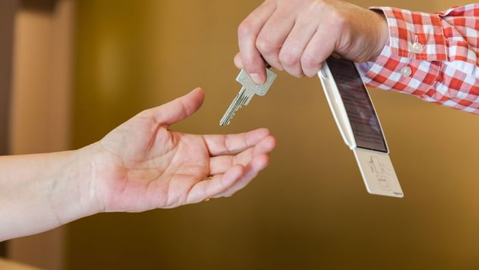 A person hand overring a room door key at Archotel
