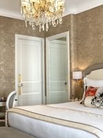 Bed under wall lamp near vanity desk in Prestige Suite – Rue de la Paix View at Hotel Westminster Paris