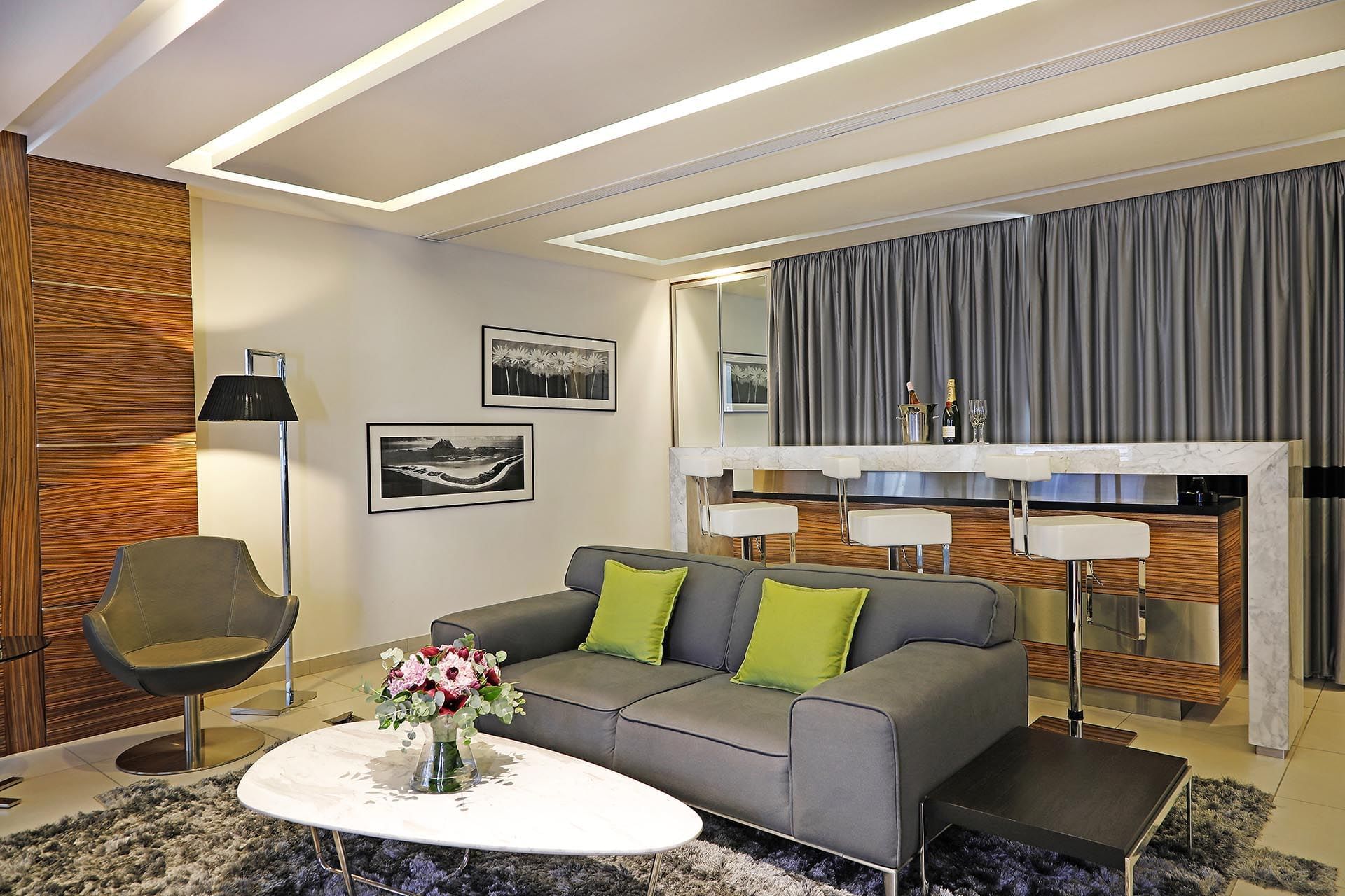 Grey sofa by a marble table and breakfast bar under recessed lights in Executive Suite at Warwick Stone 55 - Beirut