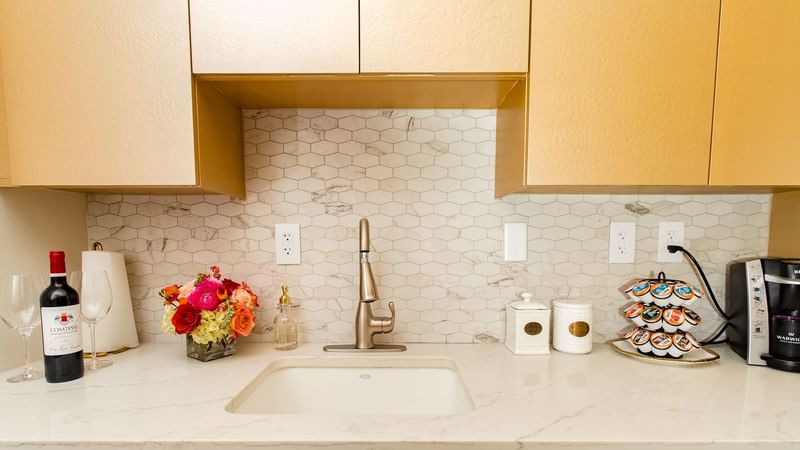 Presidential Suite kitchen with gold cabinetry, white marble countertop, and sink at Warwick Melrose Dallas