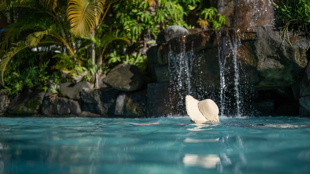 Swimmer relaxing in the pool with a hat at Tokatoka Resort - Fiji International Airport, Nadi.