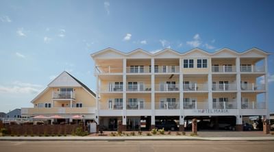 The Hotel Maria with warm yellow siding, inviting balconies, and a welcoming entrance beneath a clear sky
