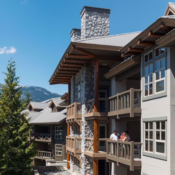 Family on a room balcony overlooking the hotel exterior at Blackcomb Springs Suites