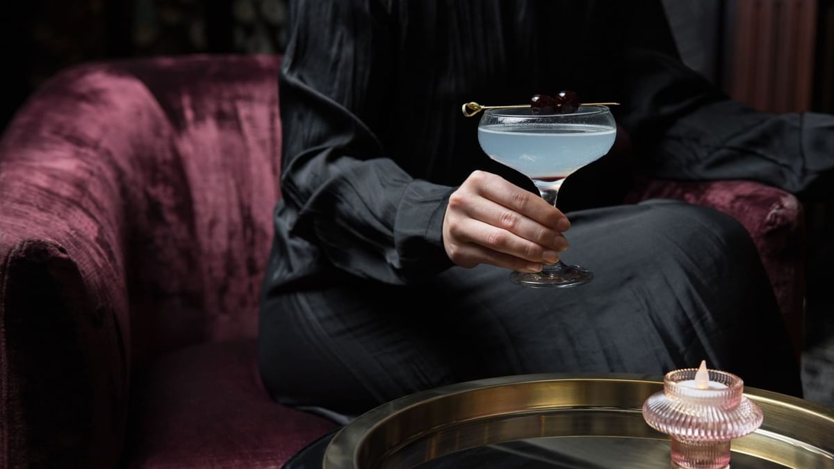 Person holding a cocktail with cherries in Minq Bar Lounge at Crown Hotels Perth