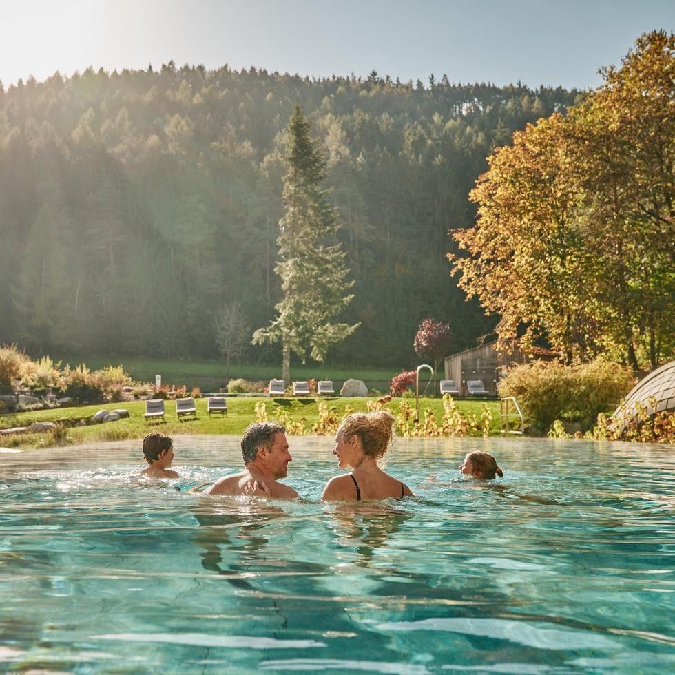 Guests enjoying an outdoor pool surrounded by golden autumn foliage and misty forest landscape for Long Stay Special Autumn