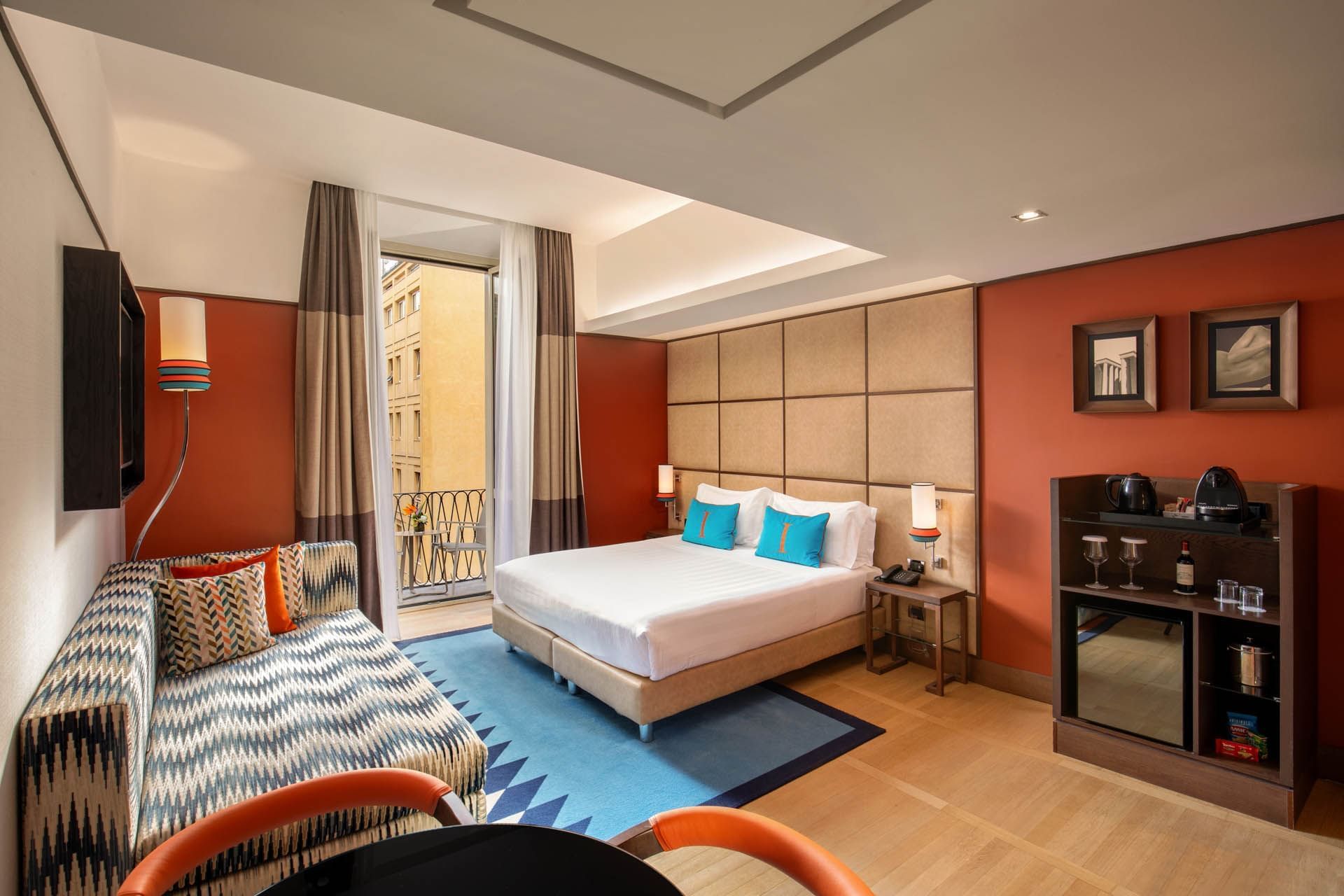 Modern Family Room at The Independent with a king bed, sofa, vibrant decor, wooden flooring, and a balcony