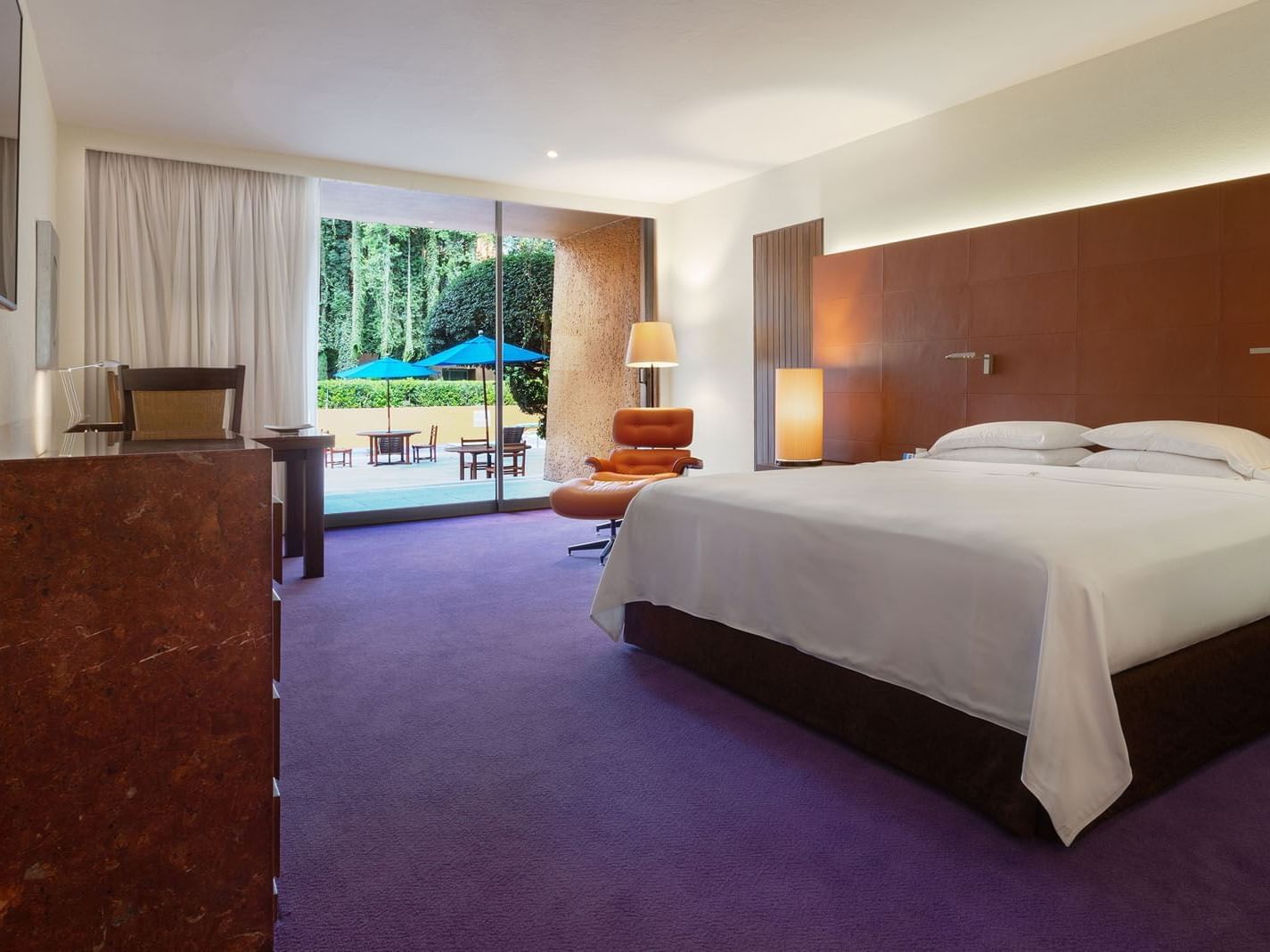 King Master Suite with purple floors and a view of blue umbrellas in a lush garden area at Camino Real Polanco Mexico