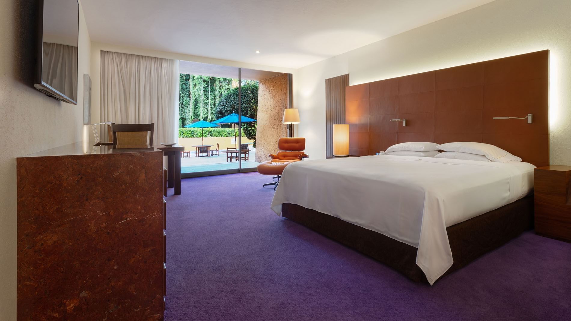 King Master Suite with purple floors and a view of blue umbrellas in a lush garden area at Camino Real Polanco Mexico