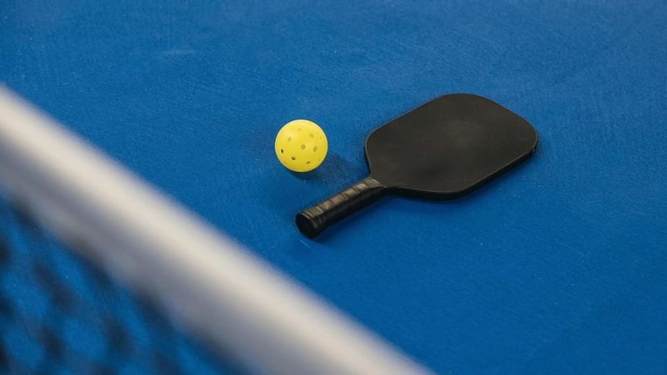 Raqueta y pelota de pickleball colocadas sobre el suelo de la cancha en Las Casitas Village.