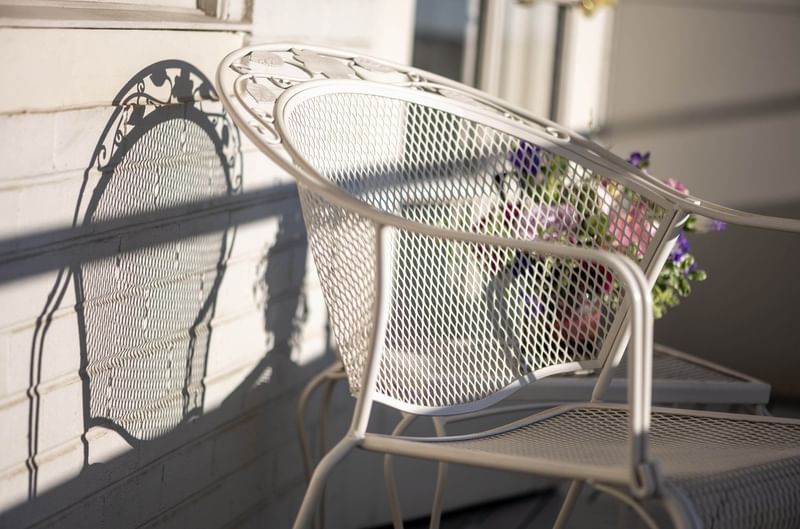 White lattice chair casting a shadow on a brick wall by a bouquet of flowers in Premier Junior Suites at Warwick Denver