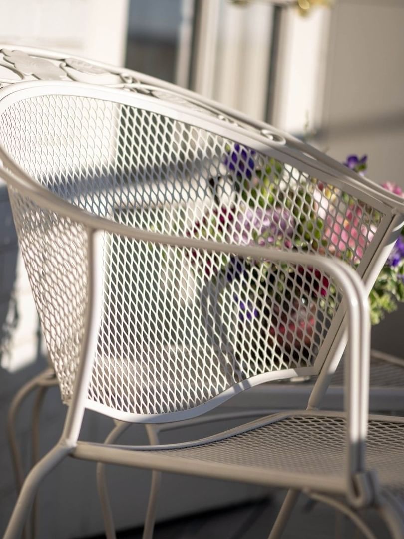 White lattice chair casting a shadow on a brick wall by a bouquet of flowers in Premier Junior Suites at Warwick Denver
