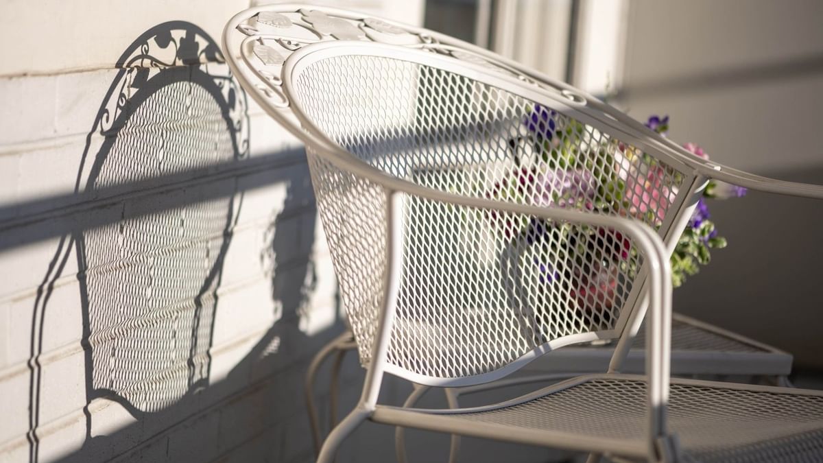 White metal chair by a brick wall under the sun on a private balcony in Classic Rooms at Warwick Denver