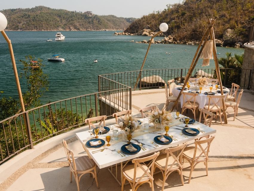 Scenic terrace event venue with marble tables overlooking a tropical bay at Camino Real III in Camino Real Acapulco Diamante