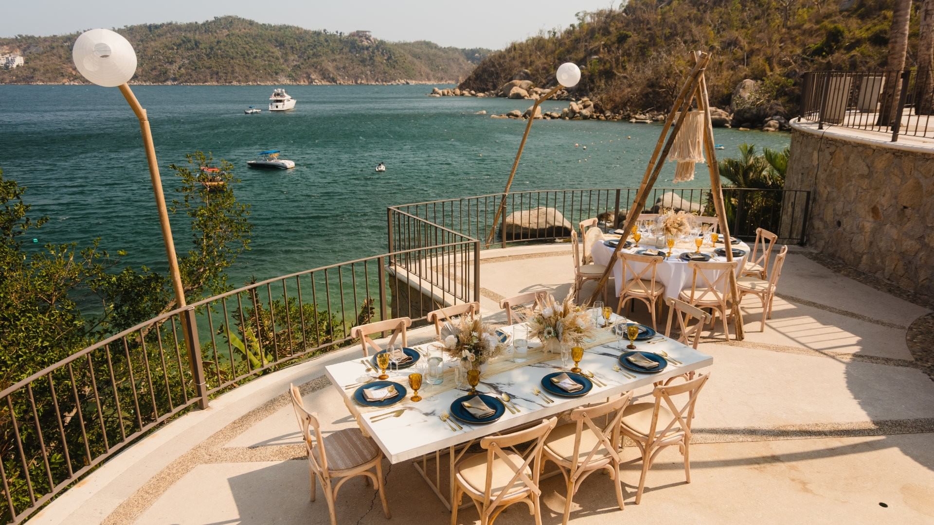 Scenic terrace event venue with marble tables overlooking a tropical bay at Camino Real III in Camino Real Acapulco Diamante