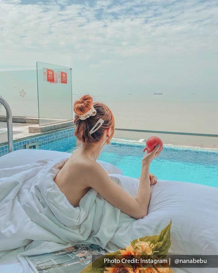 Woman posing on bed next to Lexis Hibiscus pool