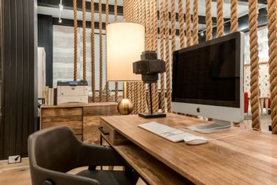 Wooden desk setup with iMac and decor elements in a 24-Hour Business Center with rope divider at The Riverwalk Plaza Hotel