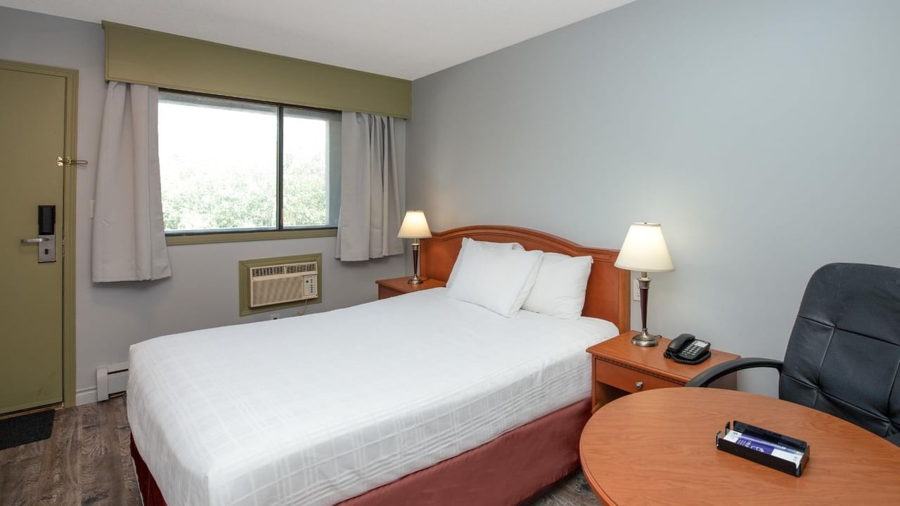 Guest room at Coast Red Deer Hotel with queen bed, desk and seating area