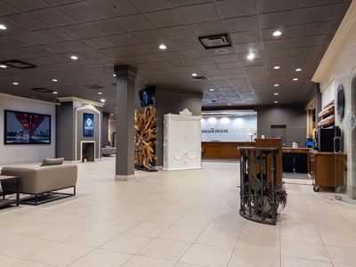 Lobby area with couch, art piece, and reception desk at Carriage House Hotel & Conference Centre