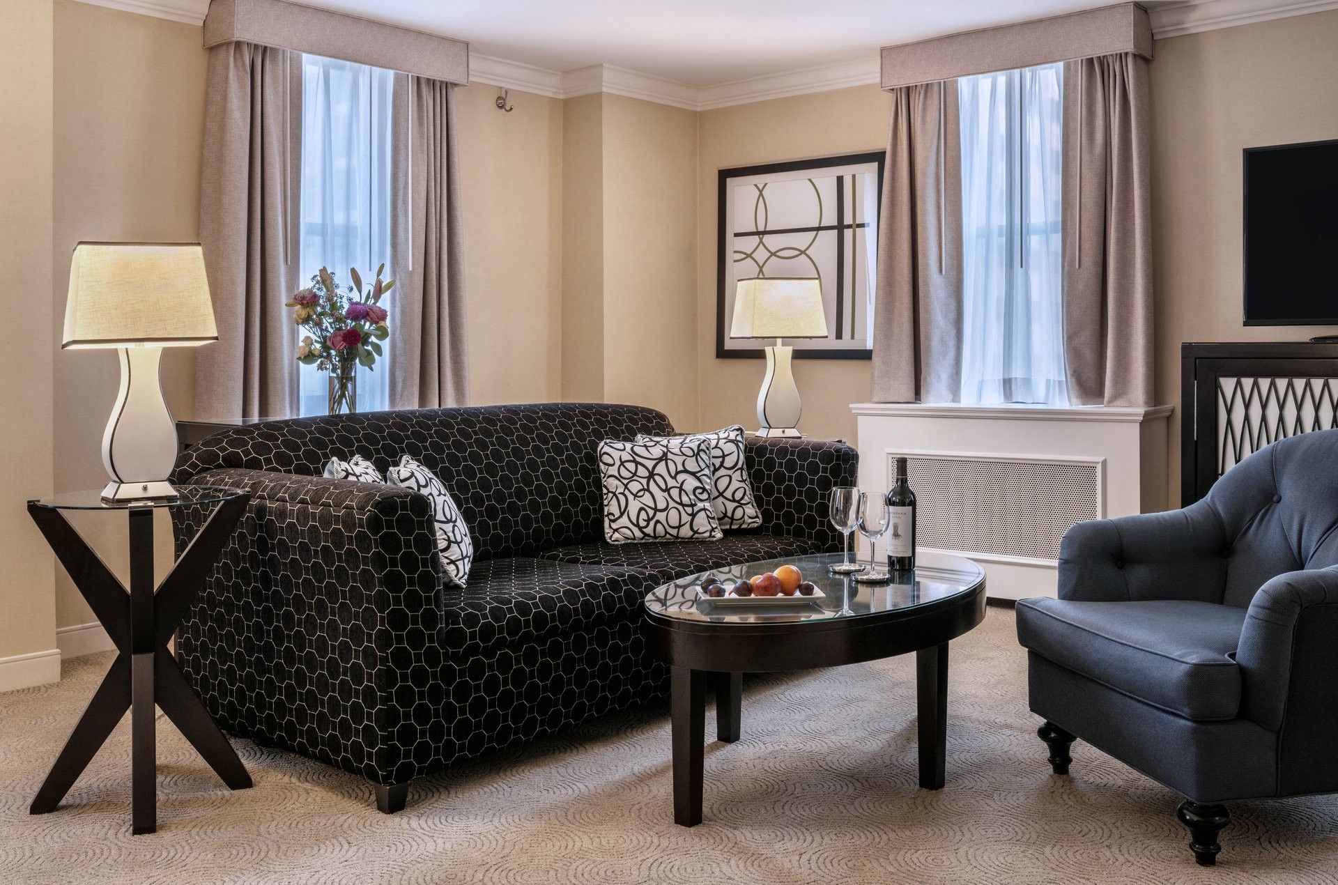 Elegant hotel room with black couch, side tables, coffee table, and armchair at Warwick Allerton Chicago Redesign