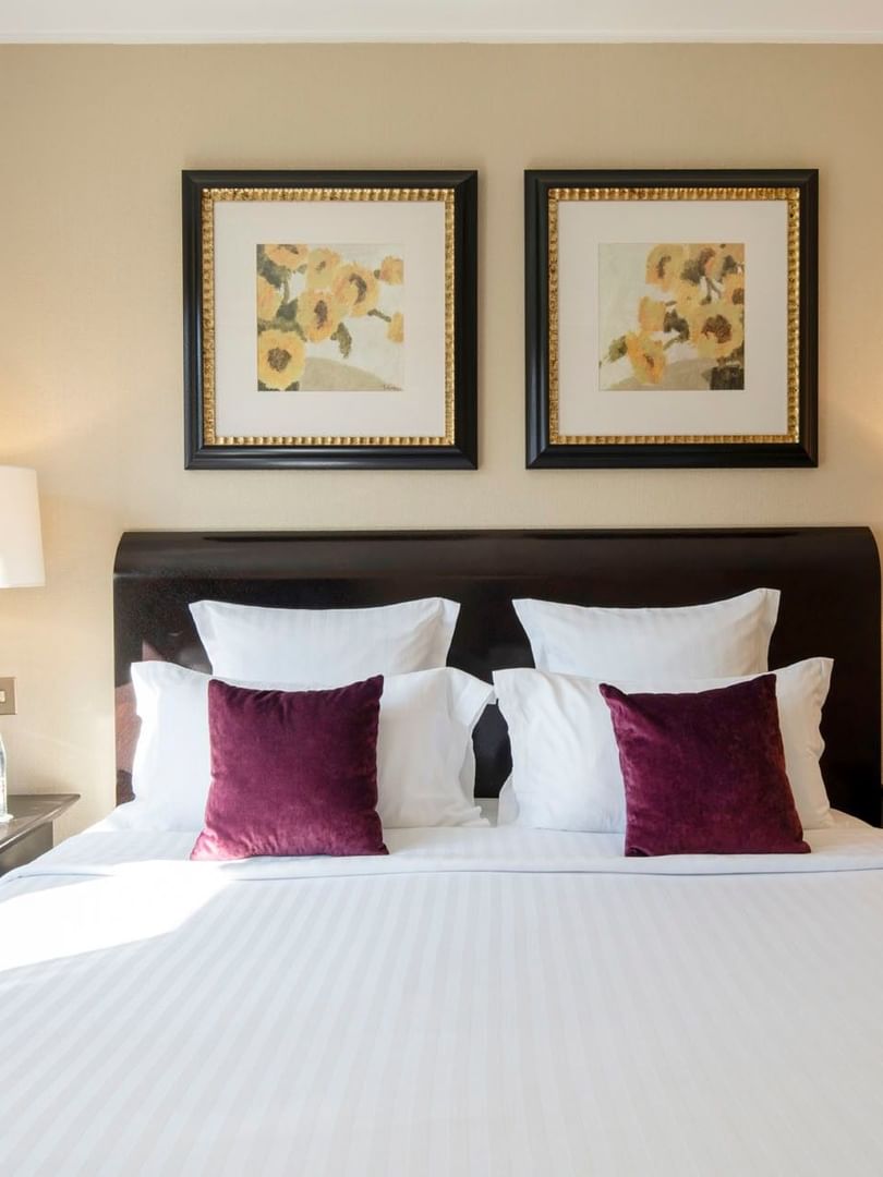Burgundy pillows on a white bed by dark side tables in Executive Suite with Terrace at Warwick Paris Champs Elysées