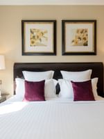 Burgundy pillows on a white bed by dark side tables in Executive Suite with Terrace at Warwick Paris Champs Elysées