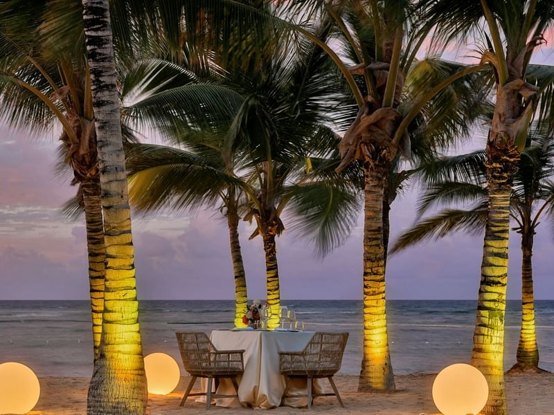 Beachside dining table with tropical palm trees in the backdrop at Live Aqua Punta Cana