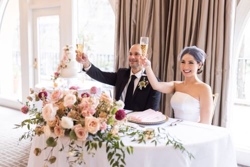 Happy bride and groom toasting in the wedding reception table at the El Prado Hotel