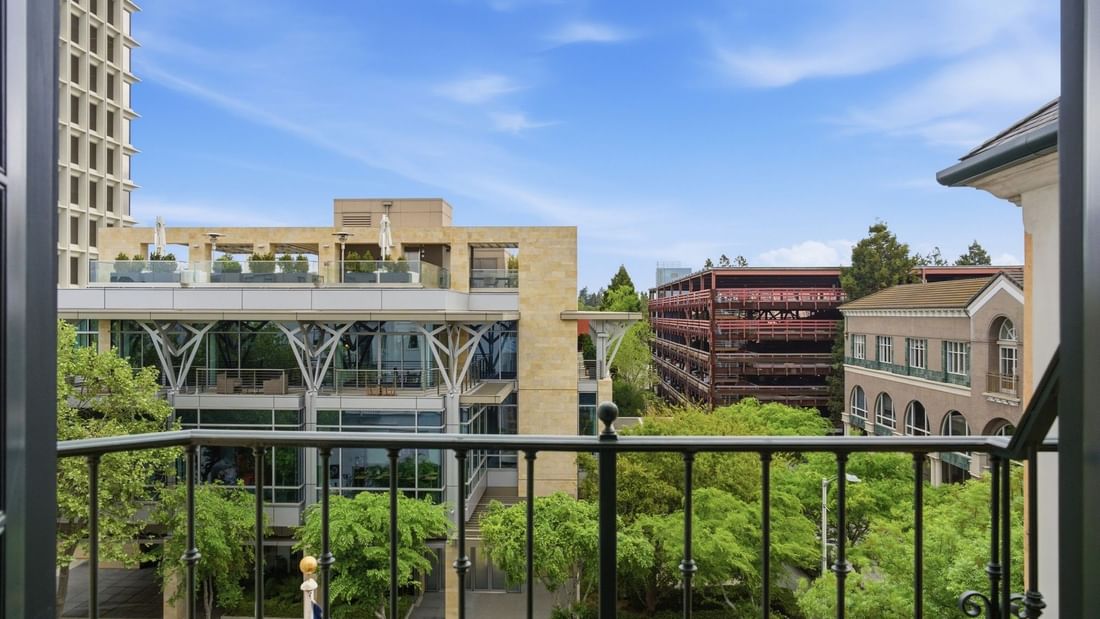 Deluxe King Suite balcony view overlooking lush greenery and urban architecture at el PRADO Hotel in Palo Alto.