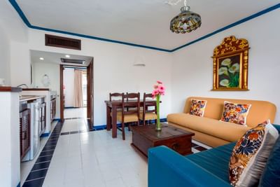 Sala de estar luminosa con sofás coloridos, mesa de comedor de madera y decoración tradicional en Los Arcos Suites