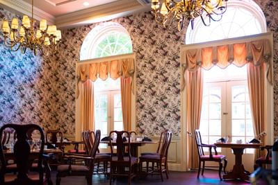 Wooden chairs by dining tables under golden chandeliers at Rodd Charlottetown Hotel, perfect for a top-rated hotel in PEI
