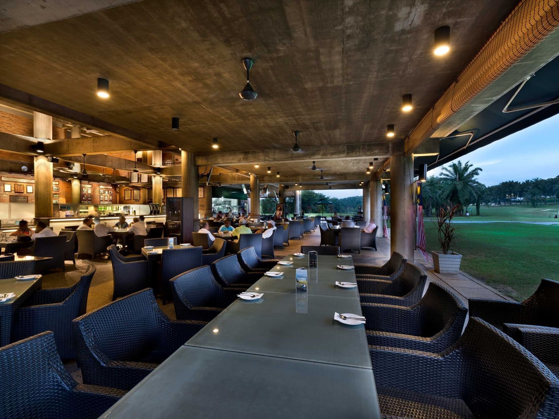 Long dining table arranged by the window overlooking the course in Golfer's Terrace at Saujana Hotel Kuala Lumpur