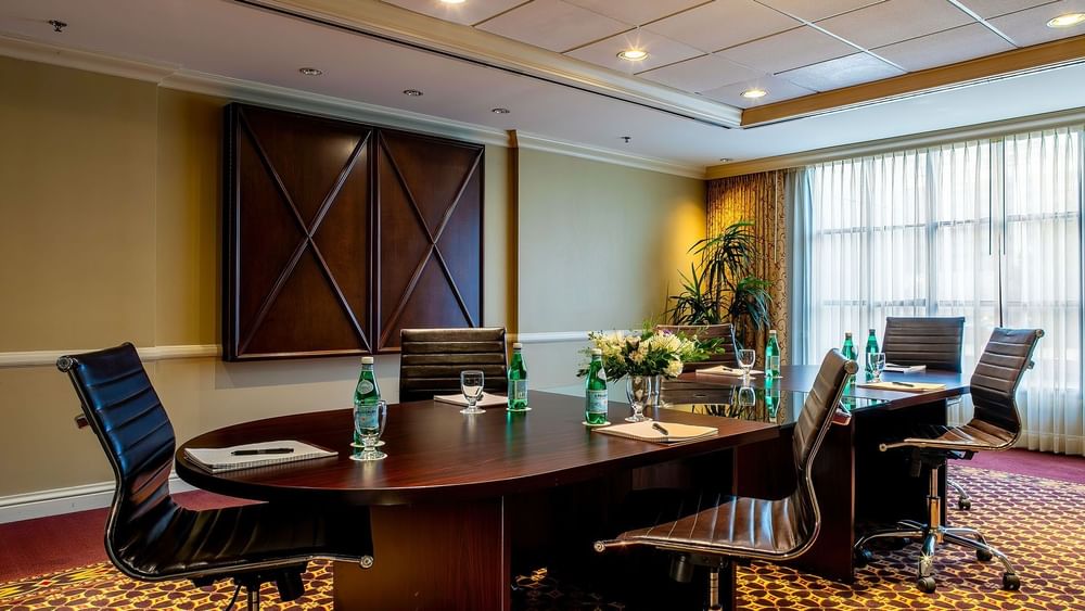 Black leather chairs by a dark wood table under a grid ceiling in Centennial at Warwick Denver