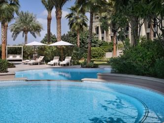 Sunbeds with canopies & trees by the pool at Palazzo Versace