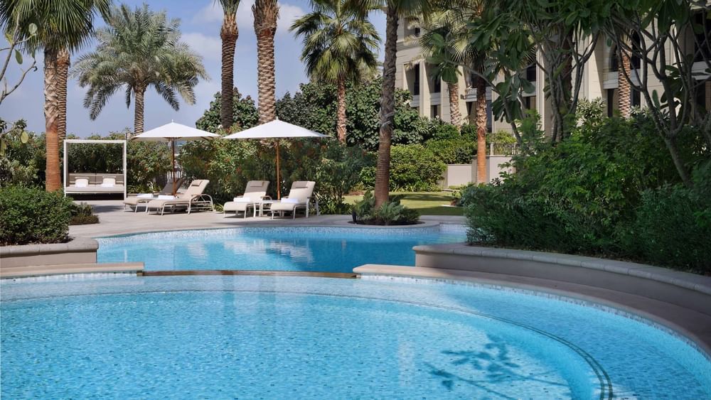 Sunbeds with canopies & trees by the pool at Palazzo Versace