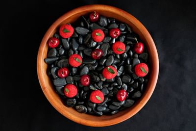 Wooden bowl filled with black pebbles, topped with red decorative fruit and cherries in Park Lounge at Park Hyatt Saigon